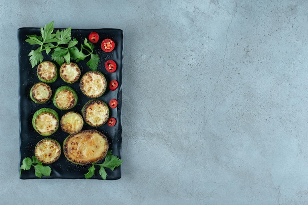 Grilled sliced zucchini on black plate.