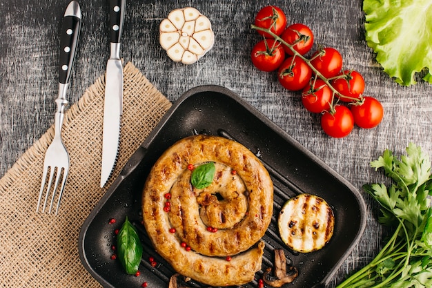 Free photo grilled snail sausage on fry pan with fresh vegetable