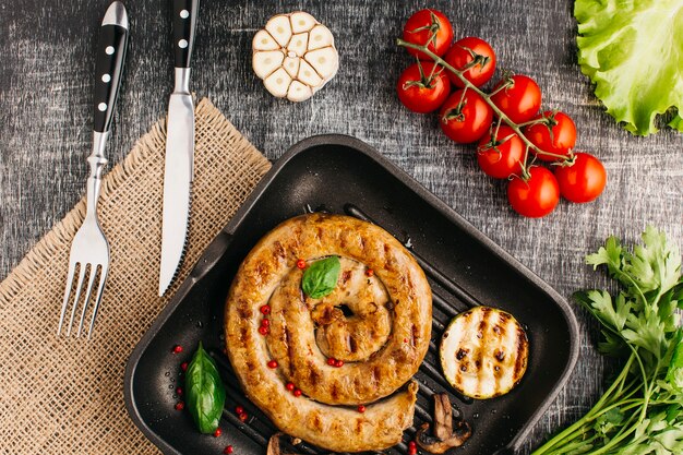 Grilled snail sausage on fry pan with fresh vegetable