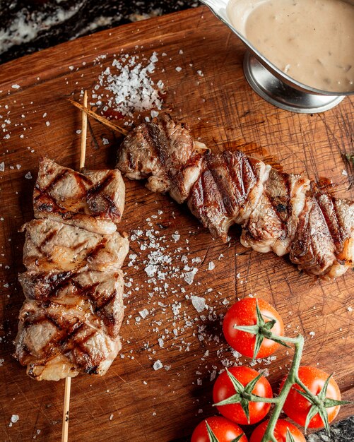 Grilled steak pieces in bamboo skewer garnished with salt and tomato