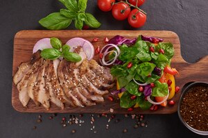 Бесплатное фото Стейк на гриле со свежими овощами, сладким перцем, помидорами, красным луком, розовым перцем и специями. домашняя вкусная еда. концепция вкусной и здоровой еды. черная каменная поверхность. стейк из свинины с салатом