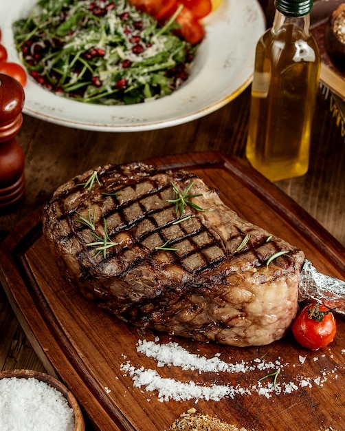 Grilled steak with salt herbs and grilled tomato served on wooden board