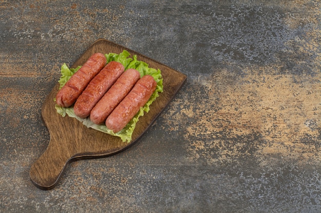 Grilled tasty sausages on wooden board.