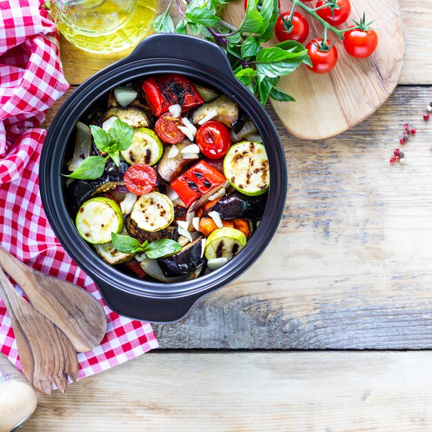 Grilled vegetables in a black ceramic pan on a wooden surface