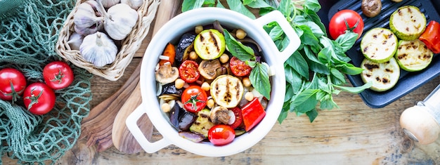 Grilled vegetables in a white ceramic pan with ingredients on a rustic surface