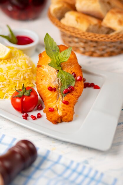 Grilled white salmon fish fillet with basilic, tomato and rice garnish.