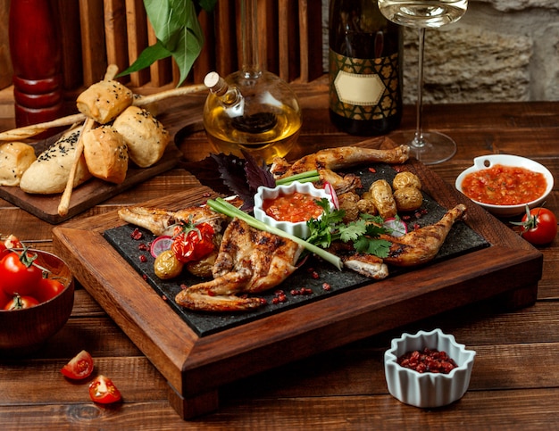 Grilled whole chicken served with tomato sauce on stone board