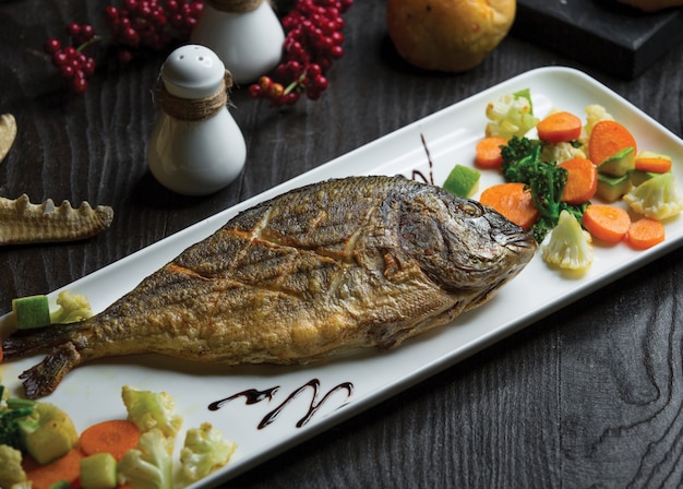 Free photo grilled whole fish with cauliflower carrot salad