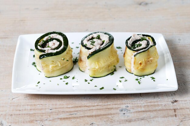 木製のテーブルにクリーム チーズとマグロを詰めたズッキーニのグリル ロール