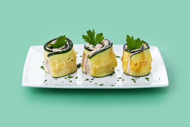 Роллы из жареных zucchini с тунцом и сливочным сыром на зеленом фоне