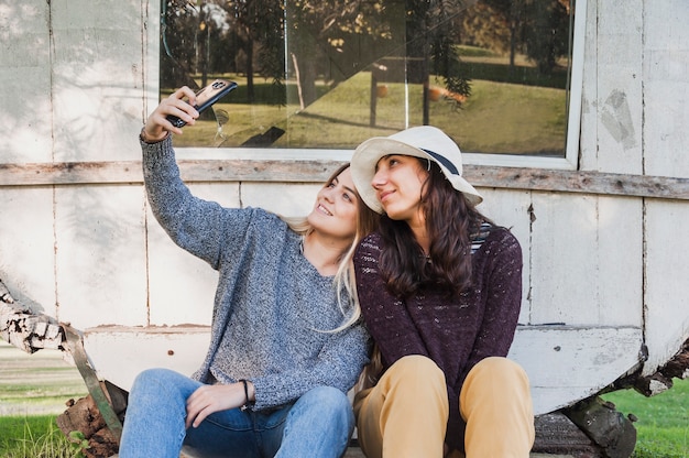 Foto gratuita griglie seduto nel parco e prendendo selfie nel telefono cellulare