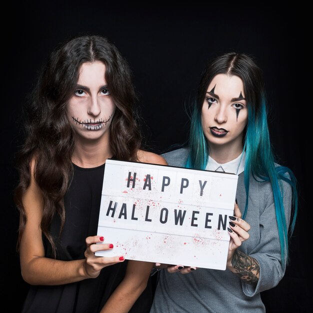 Grim young women with greeting signboard