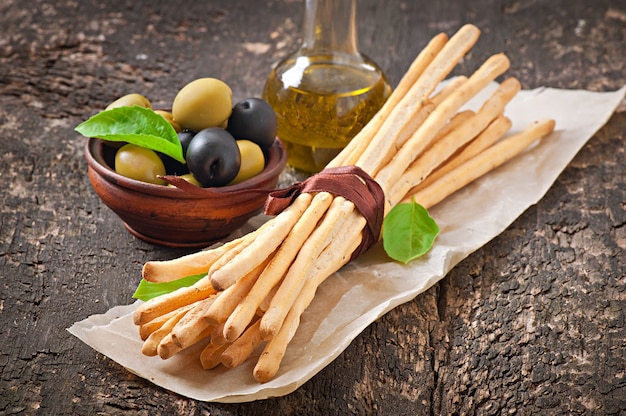 Grissini bread sticks with ham, olives, basil on old wooden