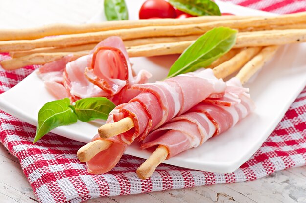 Grissini bread sticks with ham, tomato and basil