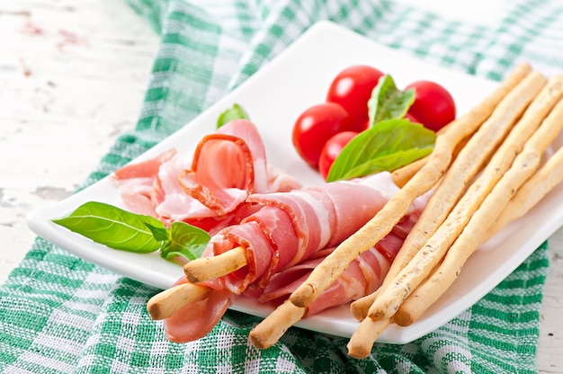 Grissini bread sticks with ham, tomato and basil