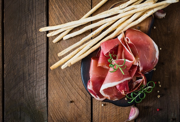 Free photo grissini bread sticks with prosciutto