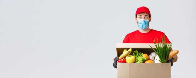 Groceries and packages delivery covid quarantine and shopping concept surprised courier in red unifo...