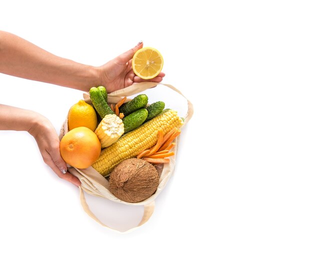 Grocery shopping with eco bag over white wall with hands. Zero waste and plastic free concept. Flat lay. Copy space.