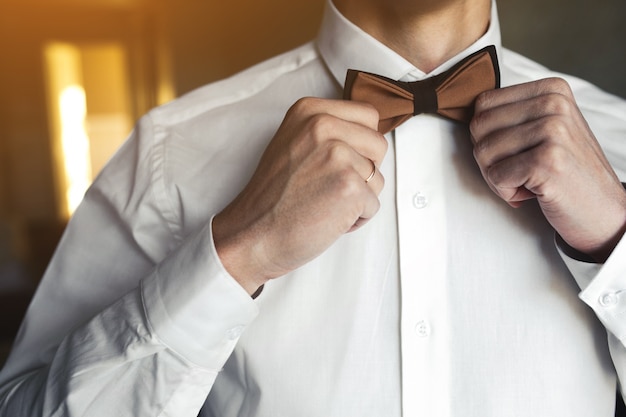 Groom adjusting bow tie