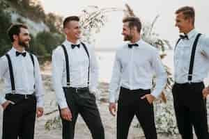 Free photo groom and best men posing on the beach