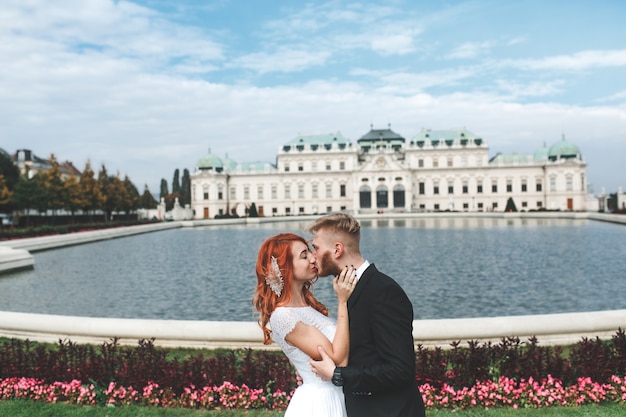 Free photo groom and bride kissing in front of a fountain