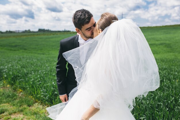 Groom and bride kissing in the meadow