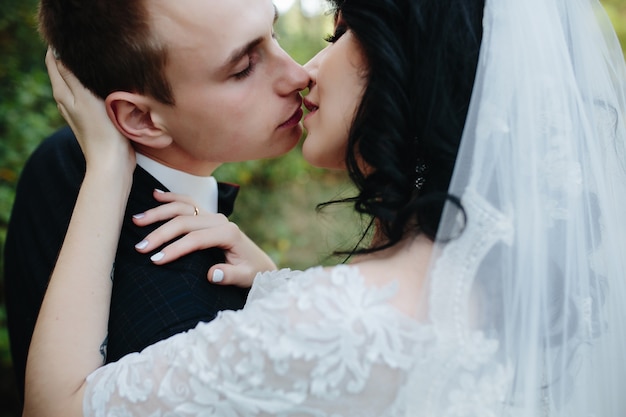 Groom and bride kissing standing outside