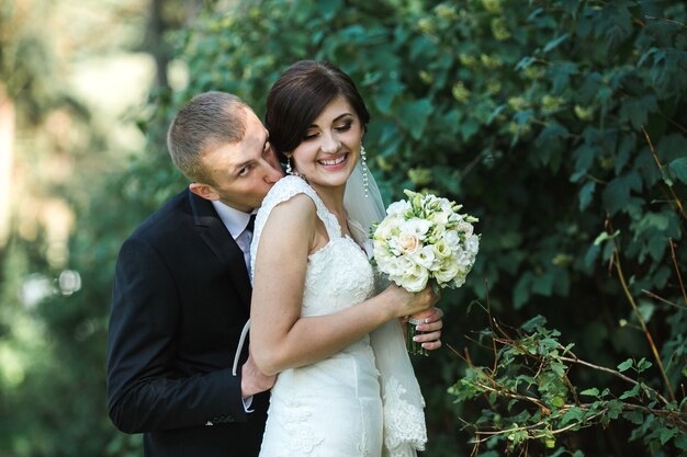 The groom comes up behind a beautiful bride