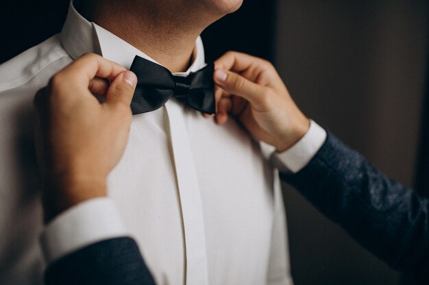 Groom dressing before the wedding ceremony, putting on a bow