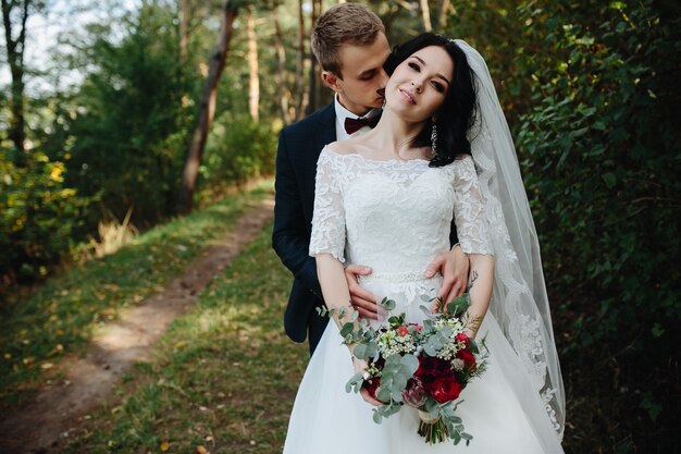 Groom embracing bride holding bouquet