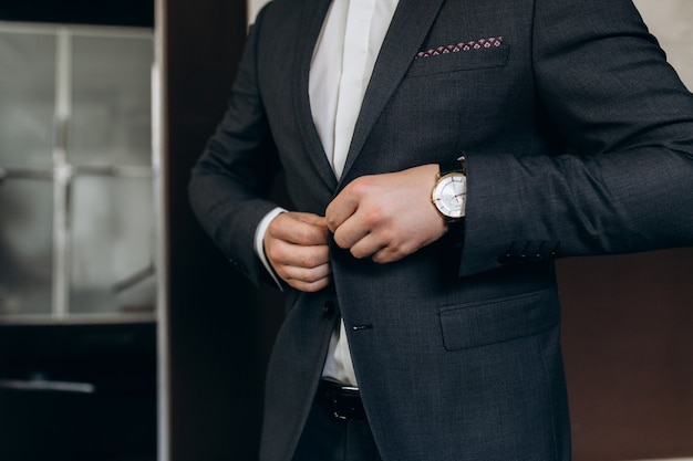 Groom fastens the buttons of his wedding suit