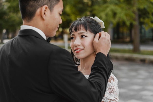 Sposo che fissa i capelli della sposa all'aperto