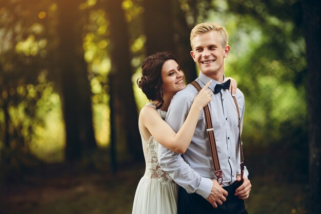 Groom gently embraces her groom in the forest