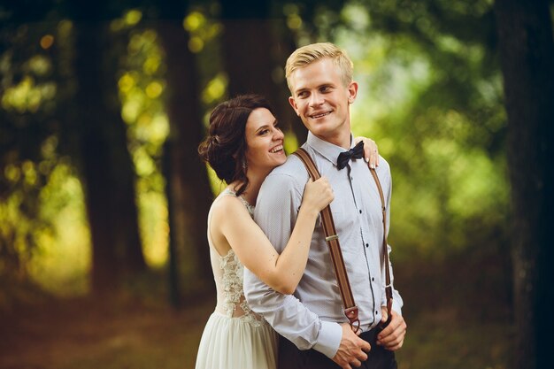 Groom gently embraces her groom in the forest