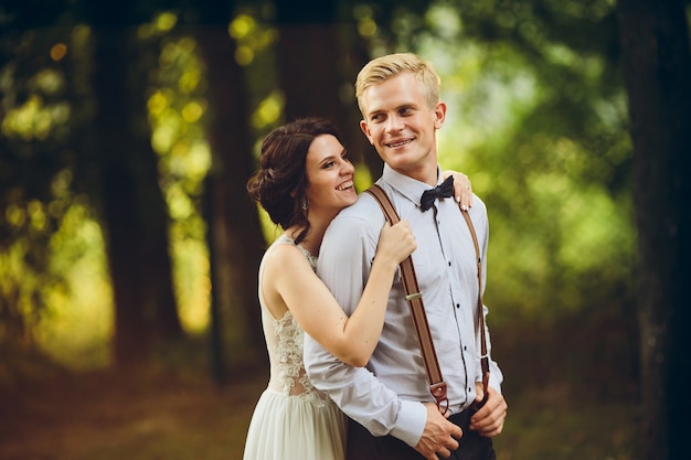 Groom gently embraces her groom in the forest