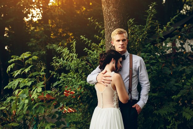 Groom gently embracing his bride in the forest