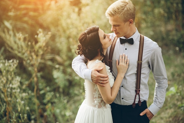 Groom gently embracing his bride in the forest