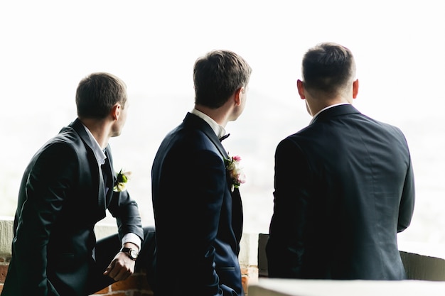 Groom and groomsmen stand on the balcony