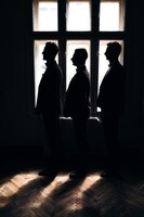 Groom and his two friends stand near a hotel window