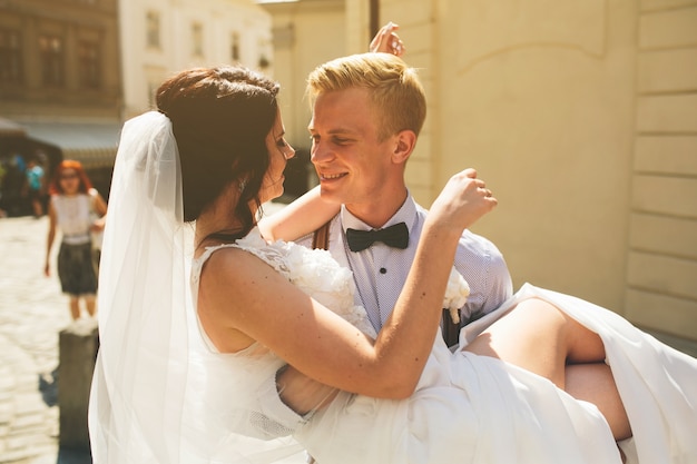 Foto gratuita lo sposo tiene la sposa tra le braccia