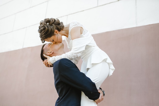 Free photo groom holds bride on his hands and kisses her