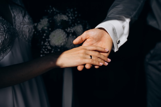 Groom holds bride's hand tender in his arm
