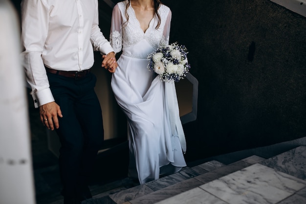 Free photo groom holds bride's hand while they go upstairs