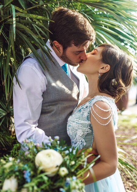 Groom holds bride tender standing in the green leaves