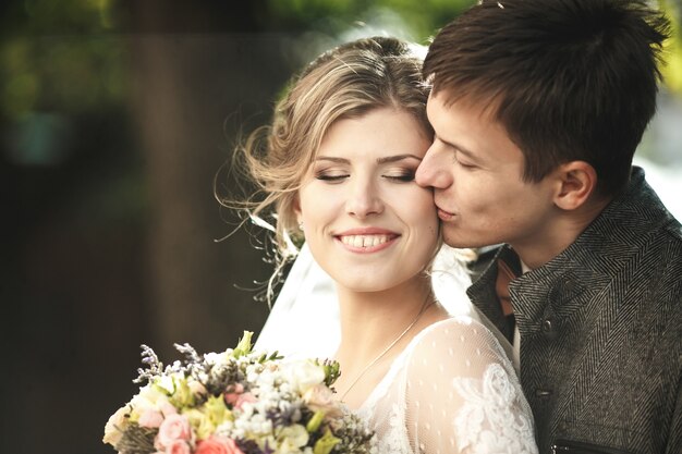 Groom hugs bride closeup portrait