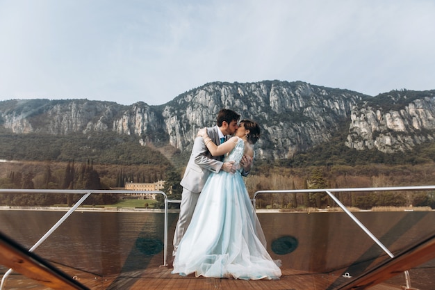 Foto gratuita lo sposo bacia la tenera sposa che sta sulla barca sopra il lago