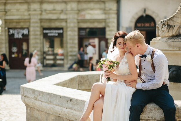 Groom kisses on the shoulder in a fountain