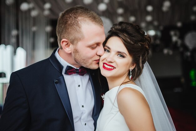 Жених целует улыбающуюся и счастливую невеста после свадебной церемонии