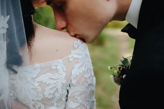 Groom kissing bride in shoulder