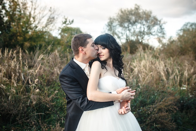 Groom kissing his wife outdoors